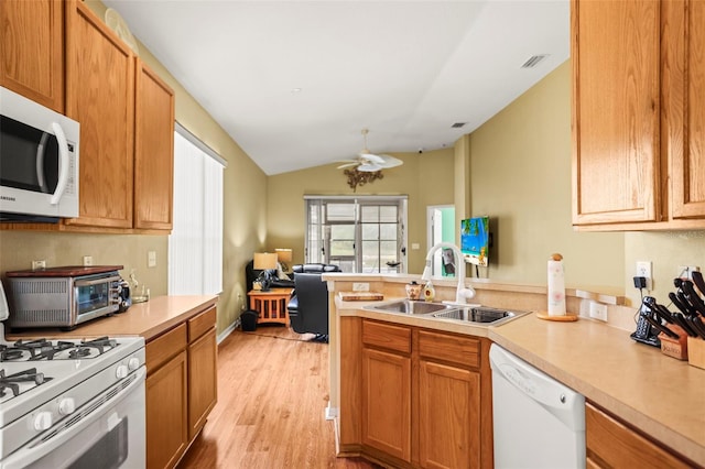 31108 Whitlock Dr, Wesley Chapel, FL 33543 - kitchen with white appliances, a sink, a peninsula, light countertops, and light wood-type flooring