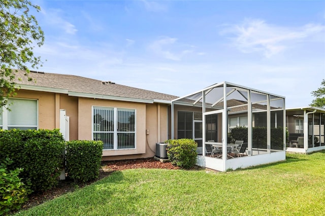 31108 Whitlock Dr, Wesley Chapel, FL 33543 - rear view of house featuring stucco siding, a lawn, roof with shingles, and central air condition unit