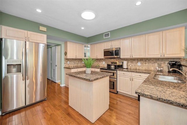 250 Rosery Rd NW Unit 218, Largo, FL 33770 - kitchen featuring stainless steel appliances, dark stone counters, light wood-type flooring, a kitchen island, and decorative backsplash