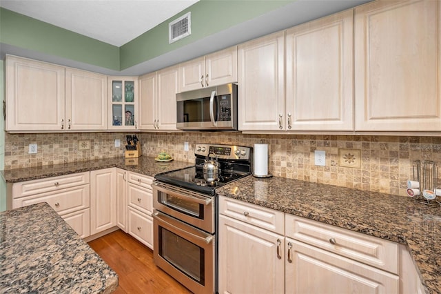 250 Rosery Rd NW Unit 218, Largo, FL 33770 - kitchen featuring stainless steel appliances, light wood-type flooring, tasteful backsplash, and dark stone counters