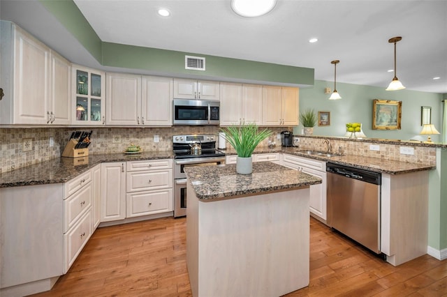 250 Rosery Rd NW Unit 218, Largo, FL 33770 - kitchen featuring appliances with stainless steel finishes, a peninsula, light wood-type flooring, tasteful backsplash, and a kitchen island
