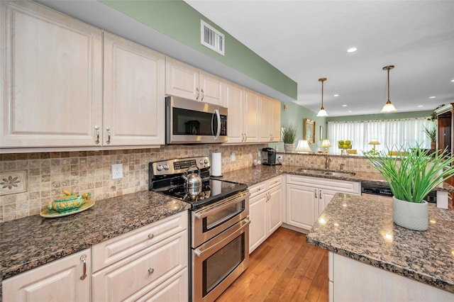 250 Rosery Rd NW Unit 218, Largo, FL 33770 - kitchen with stainless steel appliances, light wood finished floors, backsplash, a peninsula, and pendant lighting