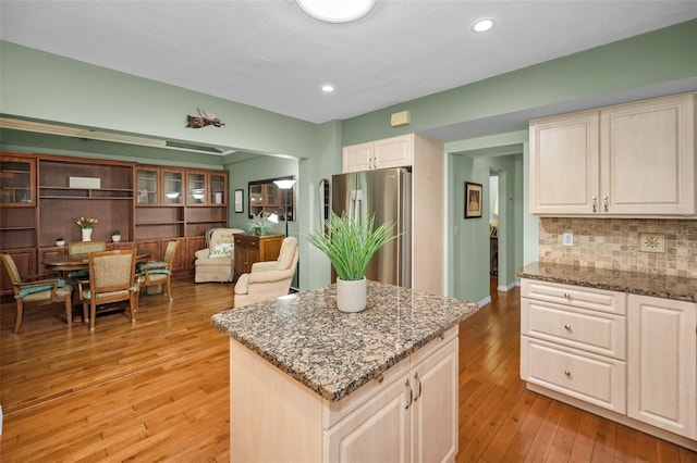250 Rosery Rd NW Unit 218, Largo, FL 33770 - kitchen featuring freestanding refrigerator, light stone counters, light wood-style floors, backsplash, and a kitchen island