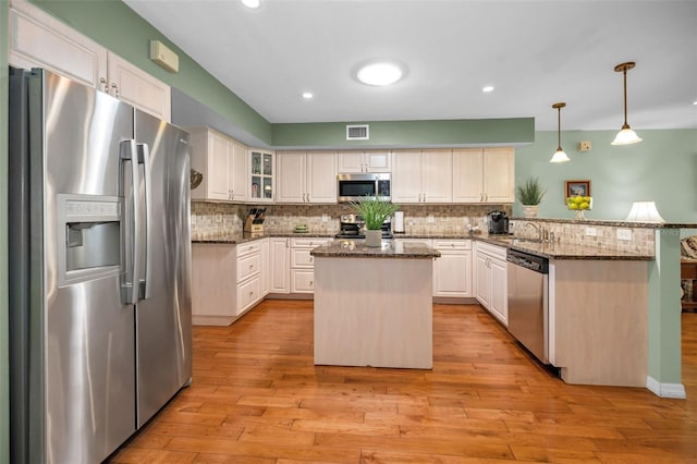 250 Rosery Rd NW Unit 218, Largo, FL 33770 - kitchen with appliances with stainless steel finishes, a peninsula, backsplash, dark stone countertops, and recessed lighting