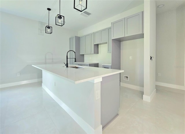 3115 52nd St W, Lehigh Acres, FL 33971 - kitchen with a sink, gray cabinetry, light tile patterned flooring, a center island with sink, and decorative light fixtures