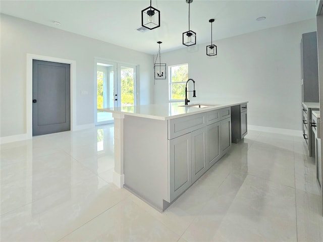 3115 52nd St W, Lehigh Acres, FL 33971 - kitchen with a sink, baseboards, light countertops, hanging light fixtures, and a center island with sink