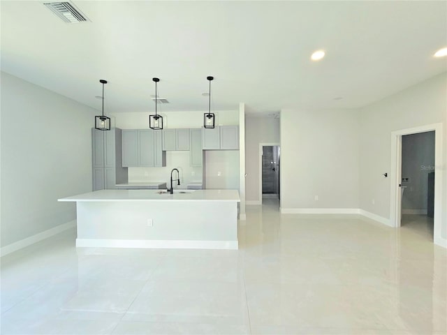 3115 52nd St W, Lehigh Acres, FL 33971 - kitchen with a center island with sink, baseboards, light countertops, a sink, and light tile patterned flooring