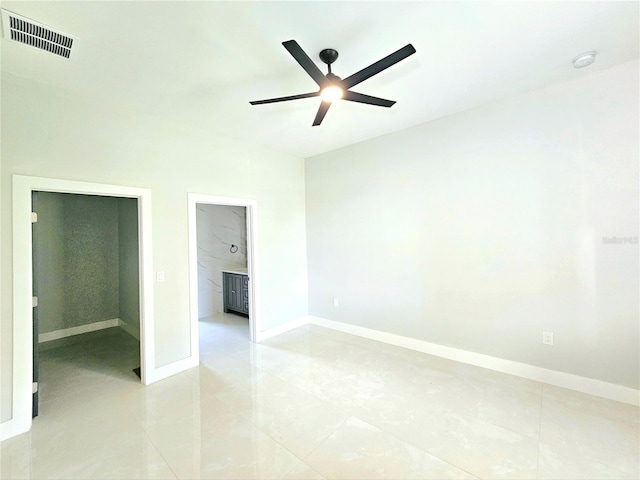 3115 52nd St W, Lehigh Acres, FL 33971 - unfurnished bedroom featuring light tile patterned floors, baseboards, a ceiling fan, a walk in closet, and ensuite bath