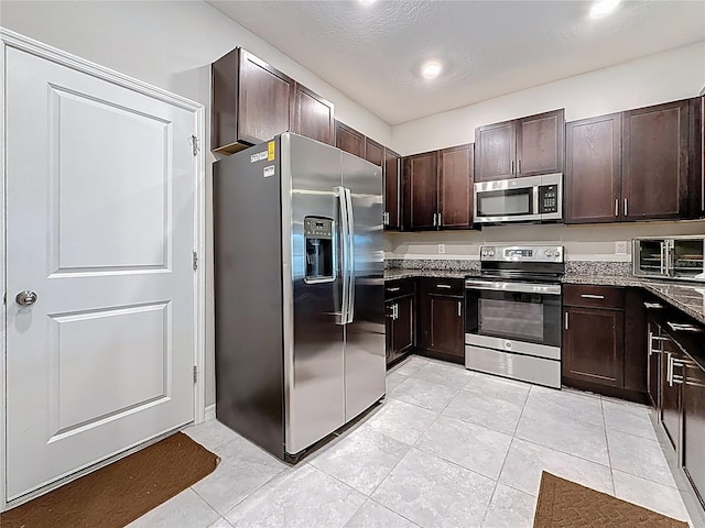 841 Royal Empress Dr, Ruskin, FL 33570 - kitchen featuring stainless steel appliances, dark brown cabinets, light stone counters, light tile patterned floors, and a textured ceiling