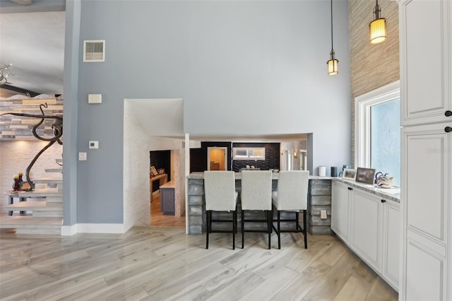 931 Gulf Blvd, Belleair Beach, FL 33786 - kitchen featuring a high ceiling, light wood-style flooring, pendant lighting, white cabinetry, and light countertops