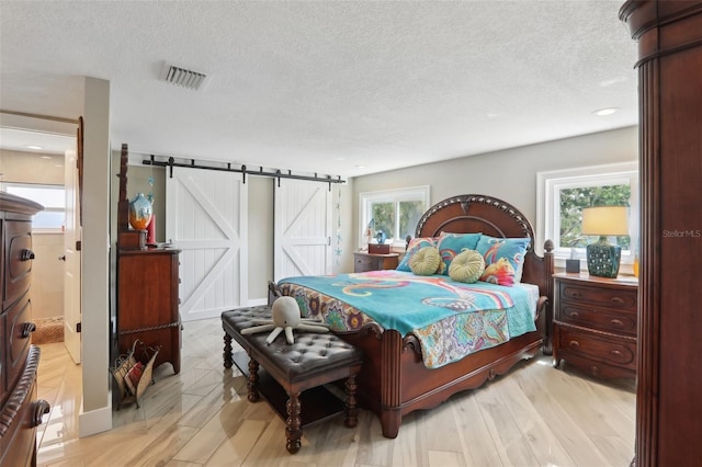 931 Gulf Blvd, Belleair Beach, FL 33786 - bedroom featuring a barn door, a textured ceiling, recessed lighting, and light wood finished floors