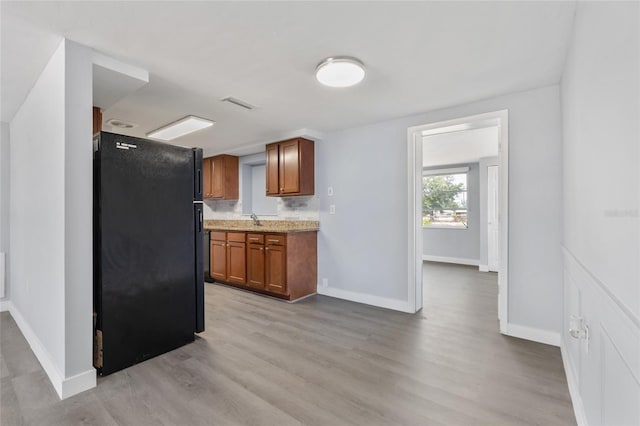 5027 Overton Dr, New Port Richey, FL 34652 - kitchen with freestanding refrigerator, brown cabinets, light countertops, and light wood-style floors