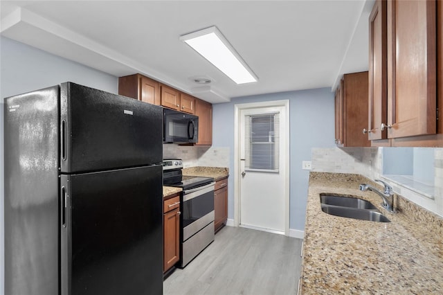 5027 Overton Dr, New Port Richey, FL 34652 - kitchen featuring black appliances, brown cabinets, tasteful backsplash, light wood-style flooring, and light stone countertops