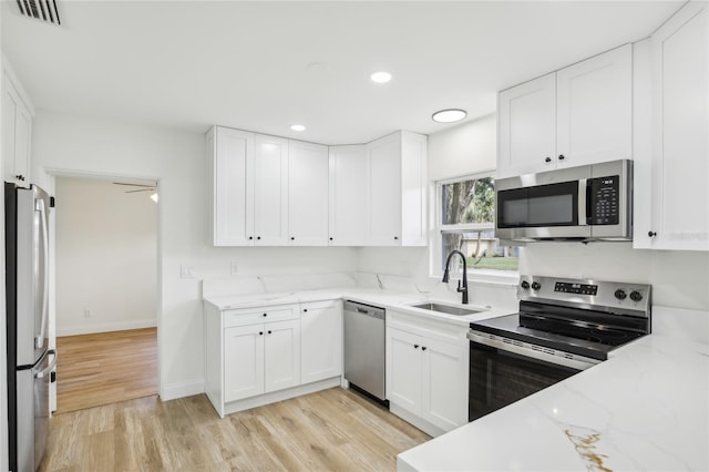 2220 3rd Ave E, Bradenton, FL 34208 - kitchen featuring appliances with stainless steel finishes, a sink, white cabinets, light wood-type flooring, and recessed lighting