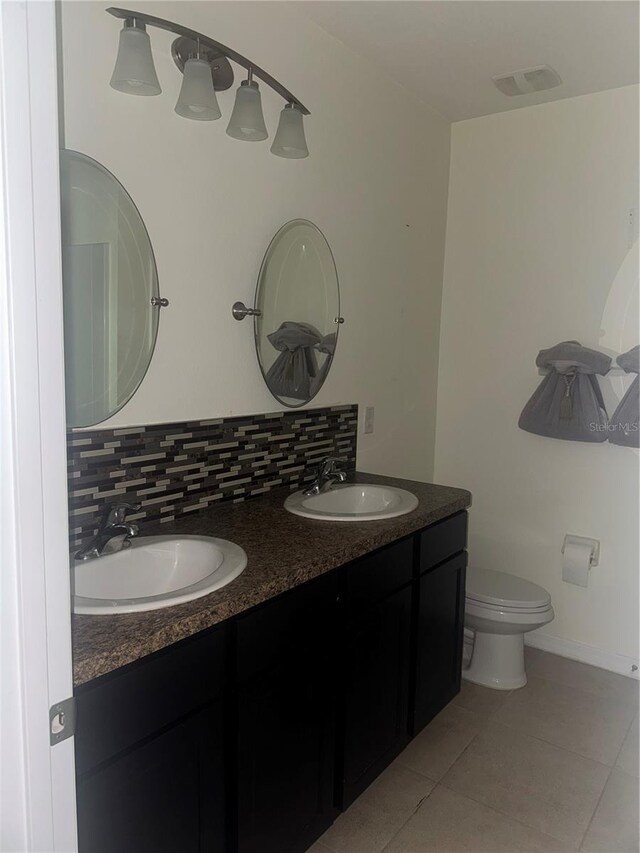 9833 Hound Chase Dr, Gibsonton, FL 33534 - full bath featuring tile patterned flooring, double vanity, decorative backsplash, toilet, and baseboards