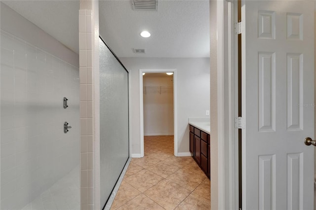 6425 Clair Shore Dr, Apollo Beach, FL 33572 - full bathroom featuring a stall shower, vanity, a spacious closet, tile patterned flooring, and a textured ceiling
