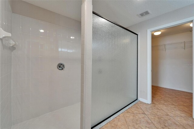 6425 Clair Shore Dr, Apollo Beach, FL 33572 - bathroom with tiled shower, a spacious closet, tile patterned flooring, and baseboards