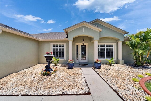 6425 Clair Shore Dr, Apollo Beach, FL 33572 - view of exterior entry with stucco siding and a shingled roof