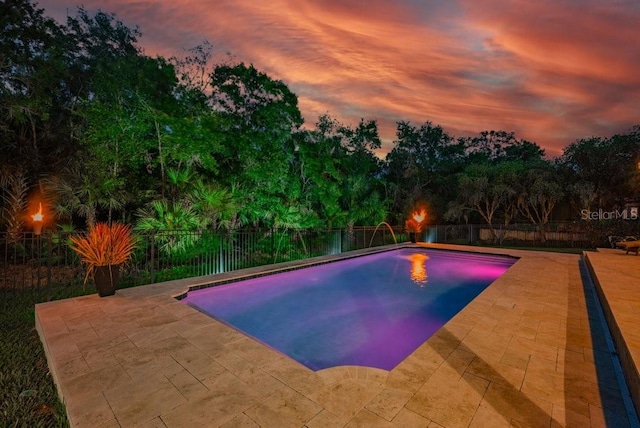 15934 Sorawater Dr, Lithia, FL 33547 - pool at dusk featuring a patio area, a fenced backyard, and view of wooded area