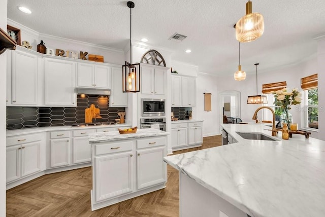 15934 Sorawater Dr, Lithia, FL 33547 - kitchen with appliances with stainless steel finishes, a kitchen island, white cabinetry, backsplash, and a textured ceiling