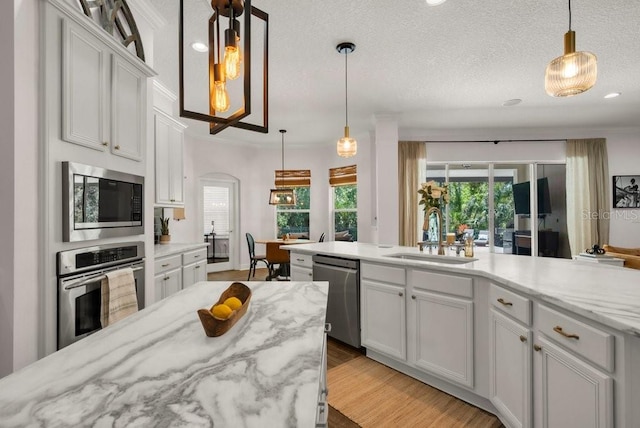 15934 Sorawater Dr, Lithia, FL 33547 - kitchen featuring appliances with stainless steel finishes, healthy amount of natural light, white cabinetry, arched walkways, and recessed lighting