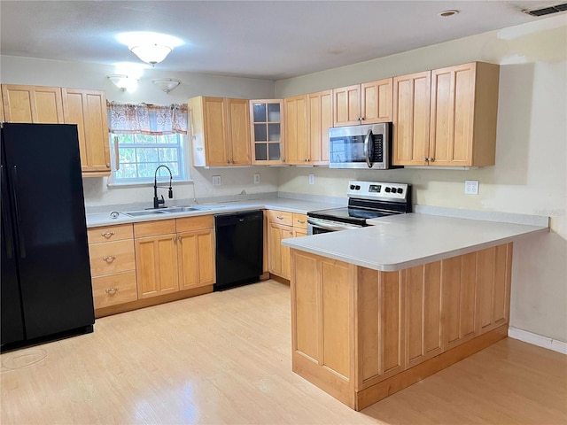 403 E Carolina Ave, Plant City, FL 33563 - kitchen with black appliances, a sink, light brown cabinetry, light wood-style flooring, and a peninsula