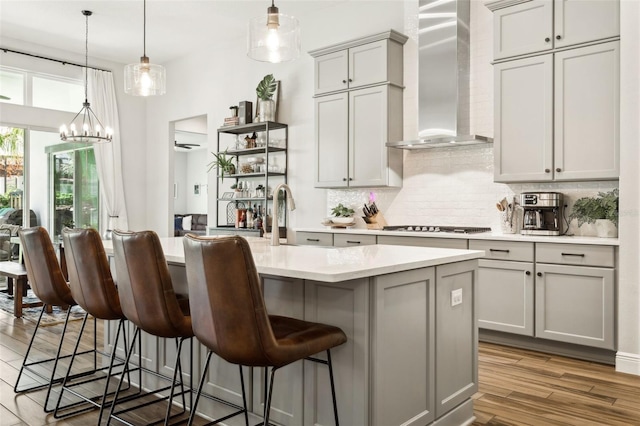 5314 Alafia Falls Dr, Lithia, FL 33547 - kitchen featuring wall chimney exhaust hood, gray cabinetry, tasteful backsplash, light countertops, and light wood finished floors