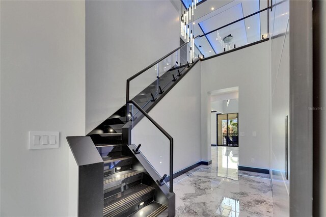 6522 Simone Shores Cir, Apollo Beach, FL 33572 - staircase featuring marble tiled floors, a towering ceiling, and baseboards