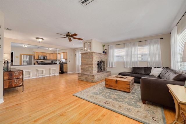 6114 7th Ave S, Gulfport, FL 33707 - living area featuring plenty of natural light, ceiling fan, light wood-type flooring, and a fireplace