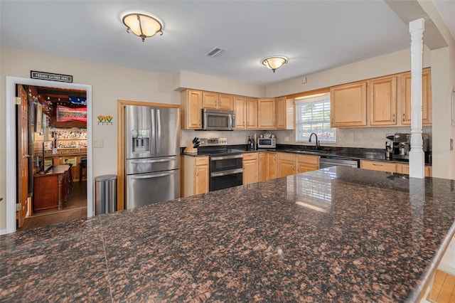 6114 7th Ave S, Gulfport, FL 33707 - kitchen featuring appliances with stainless steel finishes, light brown cabinets, backsplash, and decorative columns