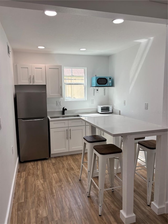 14141 Gulf Blvd Unit 5, Saint Petersburg, FL 33708 - kitchen with freestanding refrigerator, a sink, a kitchen bar, wood finished floors, and light countertops