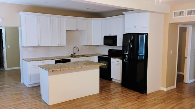 6434 Old Main St, New Port Richey, FL 34653 - kitchen with black appliances, backsplash, a center island, white cabinetry, and light wood-style floors