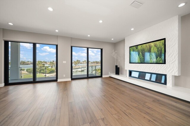 16047 Redington Dr, Redington Beach, FL 33708 - unfurnished living room featuring wood finished floors, healthy amount of natural light, recessed lighting, a fireplace, and baseboards