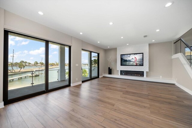 16047 Redington Dr, Redington Beach, FL 33708 - unfurnished living room featuring wood finished floors, recessed lighting, a large fireplace, a water view, and baseboards