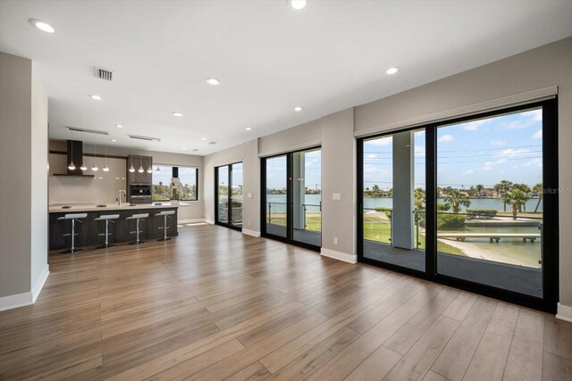 16047 Redington Dr, Redington Beach, FL 33708 - unfurnished living room featuring baseboards, wood finished floors, a water view, and recessed lighting