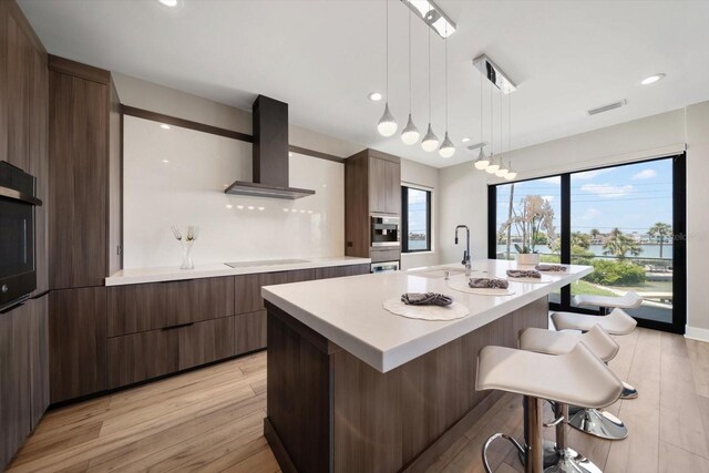 16047 Redington Dr, Redington Beach, FL 33708 - kitchen featuring wall chimney exhaust hood, modern cabinets, light countertops, a breakfast bar, and recessed lighting