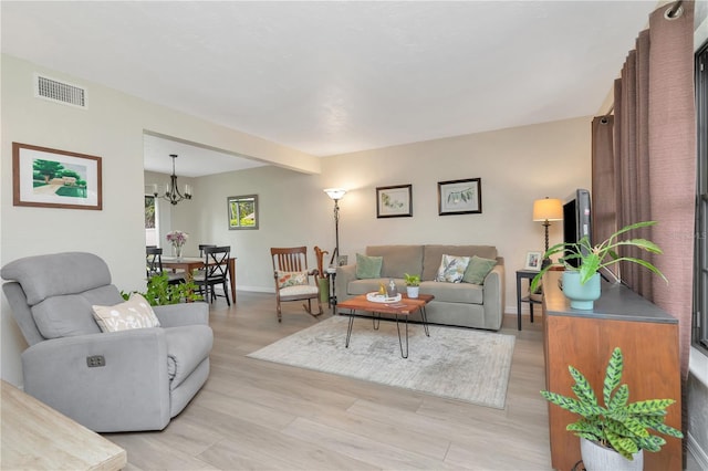 9465 126th Ave, Largo, FL 33773 - living room featuring light wood-style flooring, a chandelier, and baseboards