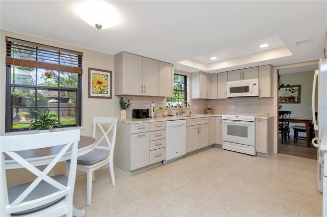 9465 126th Ave, Largo, FL 33773 - kitchen featuring white appliances, light countertops, backsplash, a raised ceiling, and light tile patterned flooring