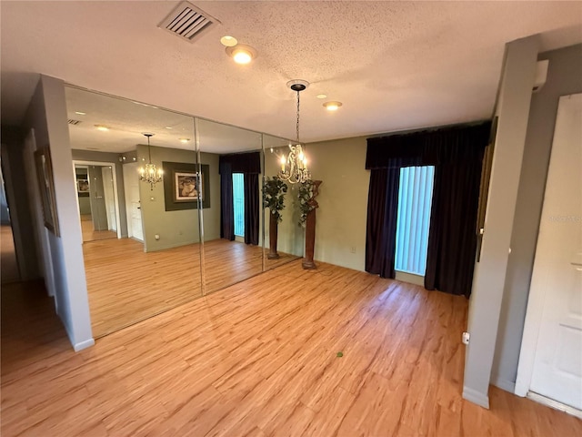 2033 Aaron Pl, Clearwater, FL 33760 - unfurnished room featuring a chandelier, light wood finished floors, a textured ceiling, and baseboards
