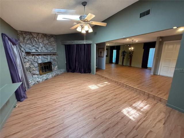 2033 Aaron Pl, Clearwater, FL 33760 - unfurnished living room with ceiling fan, light wood-style flooring, a fireplace, vaulted ceiling, and a skylight