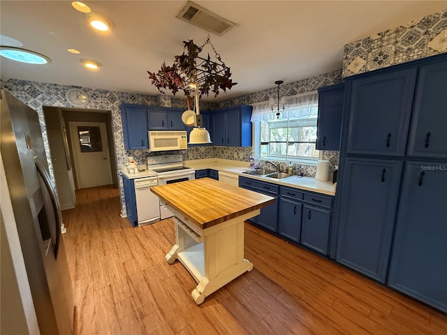 2033 Aaron Pl, Clearwater, FL 33760 - kitchen featuring butcher block countertops, blue cabinets, white appliances, a sink, and wallpapered walls