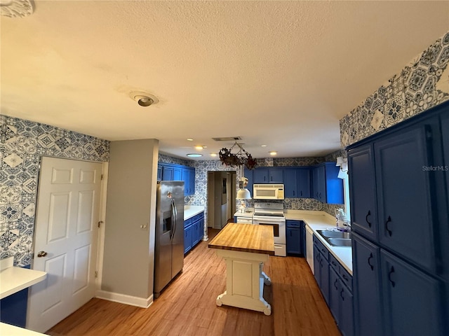 2033 Aaron Pl, Clearwater, FL 33760 - kitchen featuring white microwave, stainless steel fridge, electric range, blue cabinets, and wallpapered walls