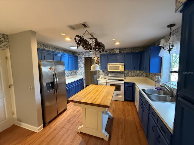 2033 Aaron Pl, Clearwater, FL 33760 - kitchen with white appliances, blue cabinets, a sink, wooden counters, and tasteful backsplash