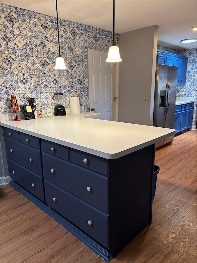 2033 Aaron Pl, Clearwater, FL 33760 - kitchen with stainless steel fridge with ice dispenser, blue cabinets, wallpapered walls, wood finished floors, and light countertops