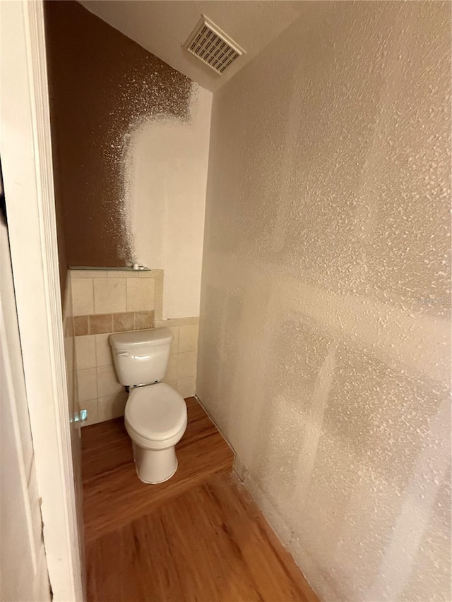 2033 Aaron Pl, Clearwater, FL 33760 - bathroom with wood finished floors, toilet, tile walls, and a wainscoted wall