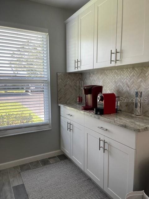 2714 60th Avenue Terrace W Unit 12D, Bradenton, FL 34207 - kitchen featuring decorative backsplash, white cabinets, baseboards, and light stone counters