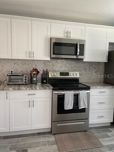 2714 60th Avenue Terrace W Unit 12D, Bradenton, FL 34207 - kitchen with stainless steel appliances, white cabinets, light stone counters, and decorative backsplash