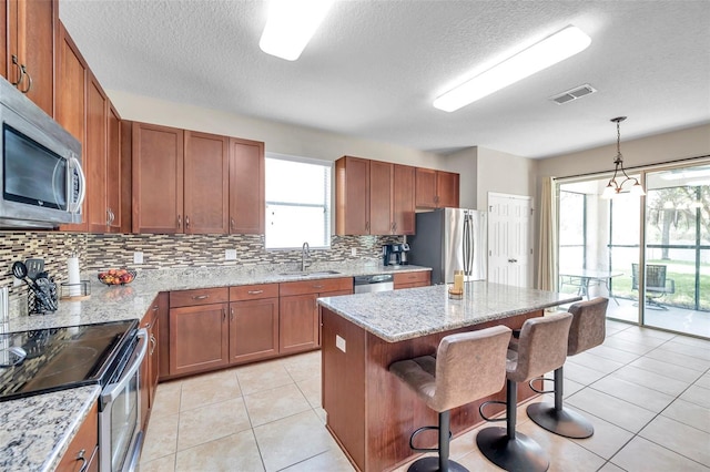 10833 Breaking Rocks Dr, Tampa, FL 33647 - kitchen with stainless steel appliances, a sink, a kitchen bar, brown cabinets, and decorative backsplash