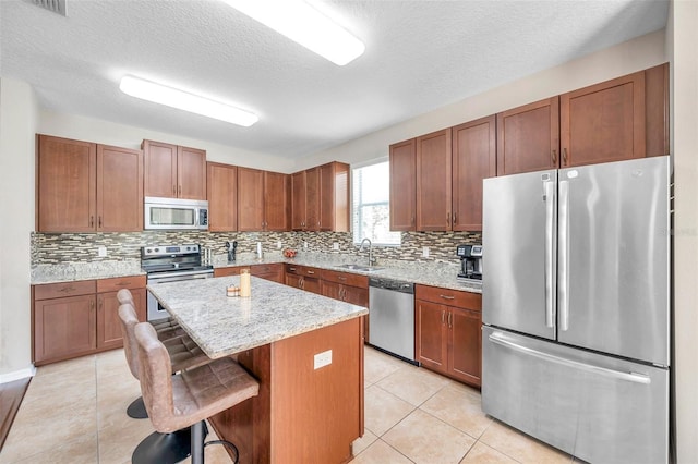 10833 Breaking Rocks Dr, Tampa, FL 33647 - kitchen featuring appliances with stainless steel finishes, a sink, a kitchen island, backsplash, and a textured ceiling