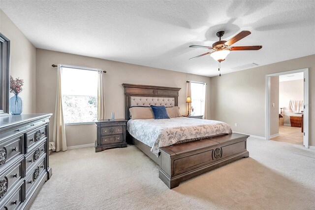 10833 Breaking Rocks Dr, Tampa, FL 33647 - bedroom featuring light carpet, baseboards, ensuite bathroom, a ceiling fan, and a textured ceiling